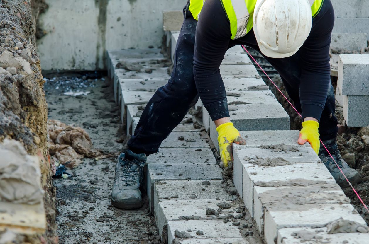 Masonry professional setting concrete blocks in mortar