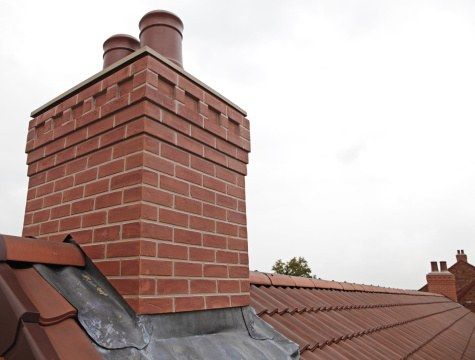 Brick chimney with a cap above a shingled roof
