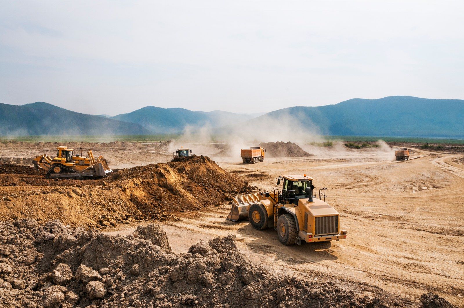 Earthmoving equipment working across a large excavated construction site