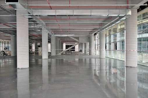 Broad concrete floor inside an open commercial building with exposed services
