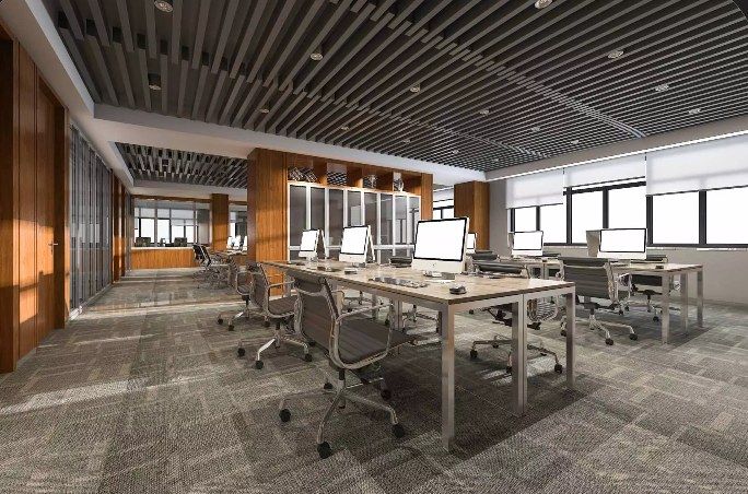 Open office interior with workstations, exposed ceiling details and large windows