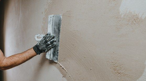 Hand applying a textured stucco finish to a light-colored wall